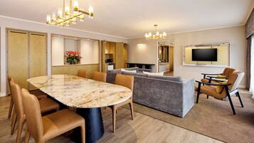 A modern living room with a marble dining table, leather sofas, and a TV mounted on the wall.