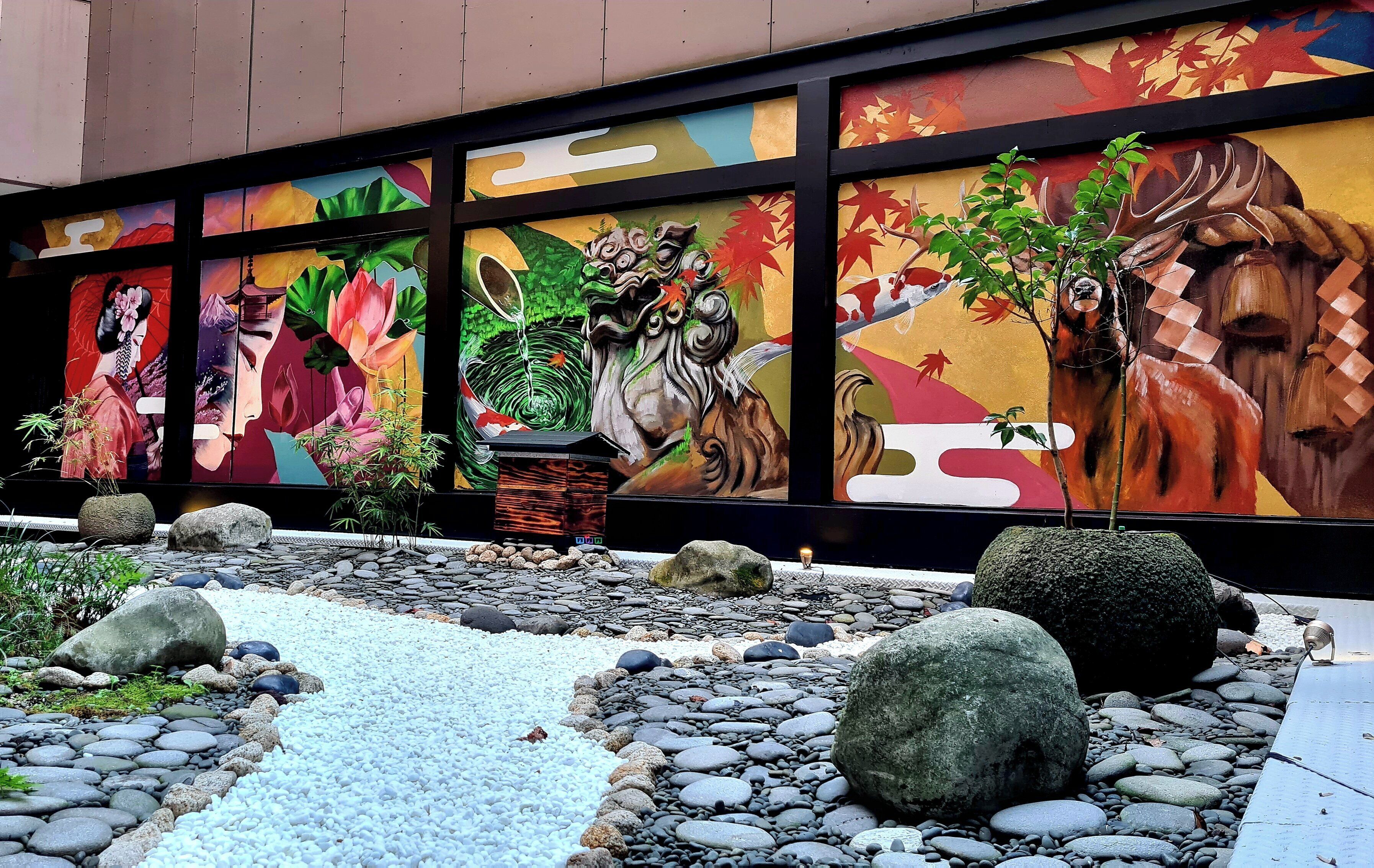 A mural with traditional Asian art, a koi pond, and a small tree.