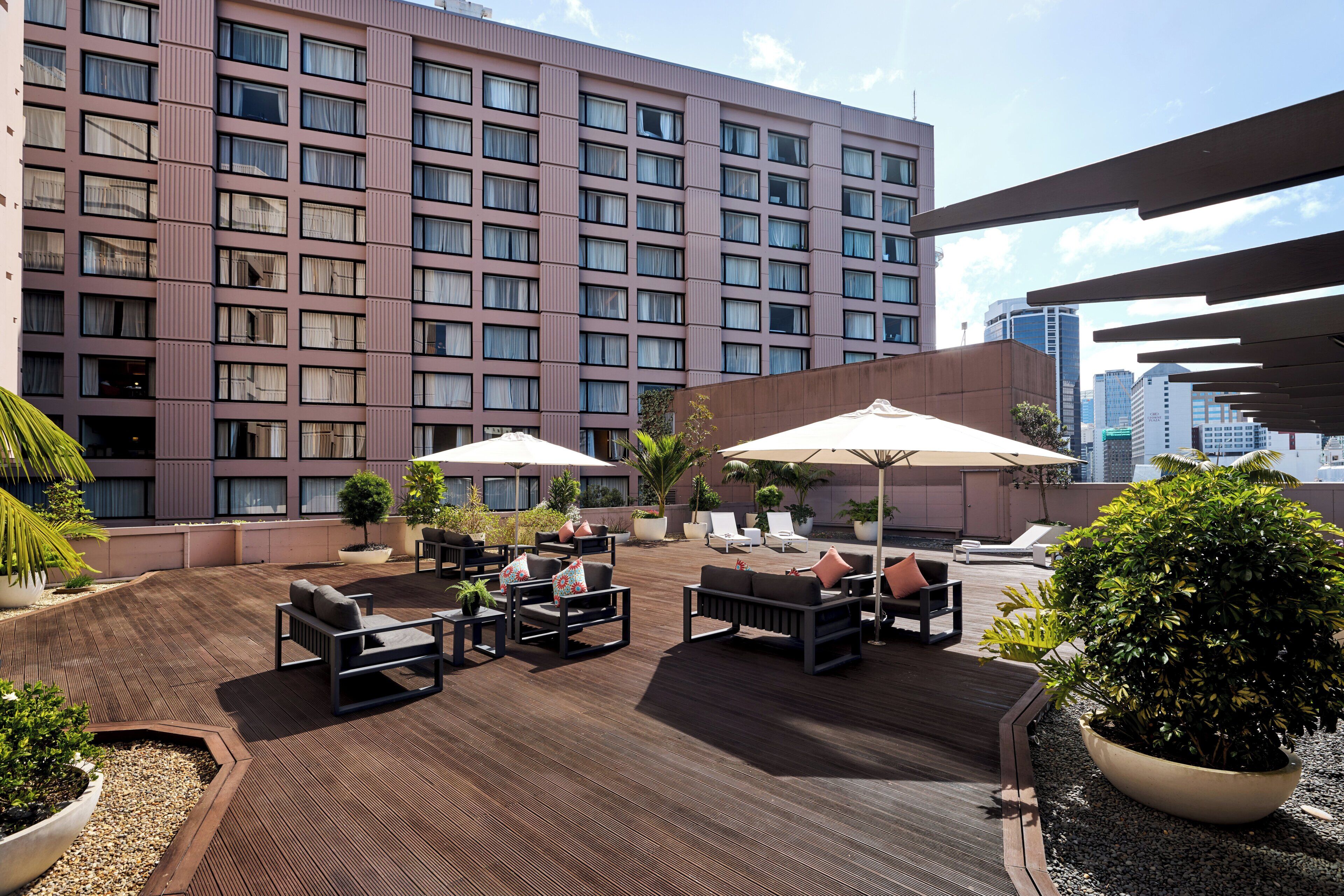 A rooftop patio with outdoor seating, umbrellas, and potted plants.