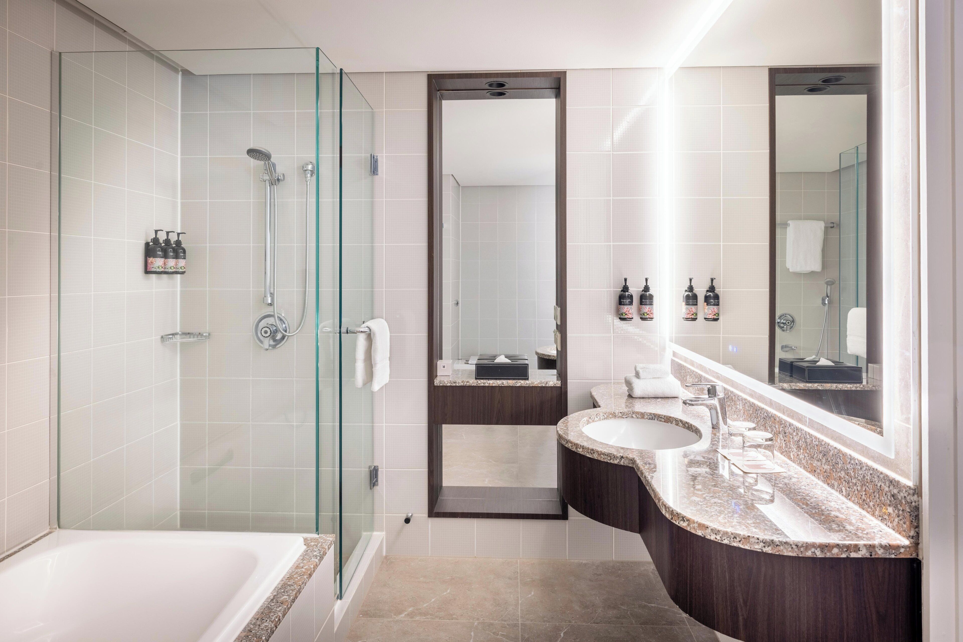 A modern bathroom with a glass-enclosed shower, a freestanding bathtub, and a vanity with a large mirror.