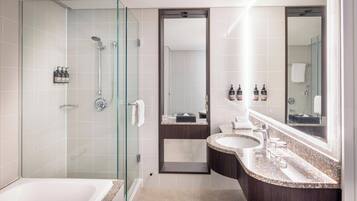 A modern bathroom with a glass-enclosed shower, a freestanding bathtub, and a vanity with a large mirror.