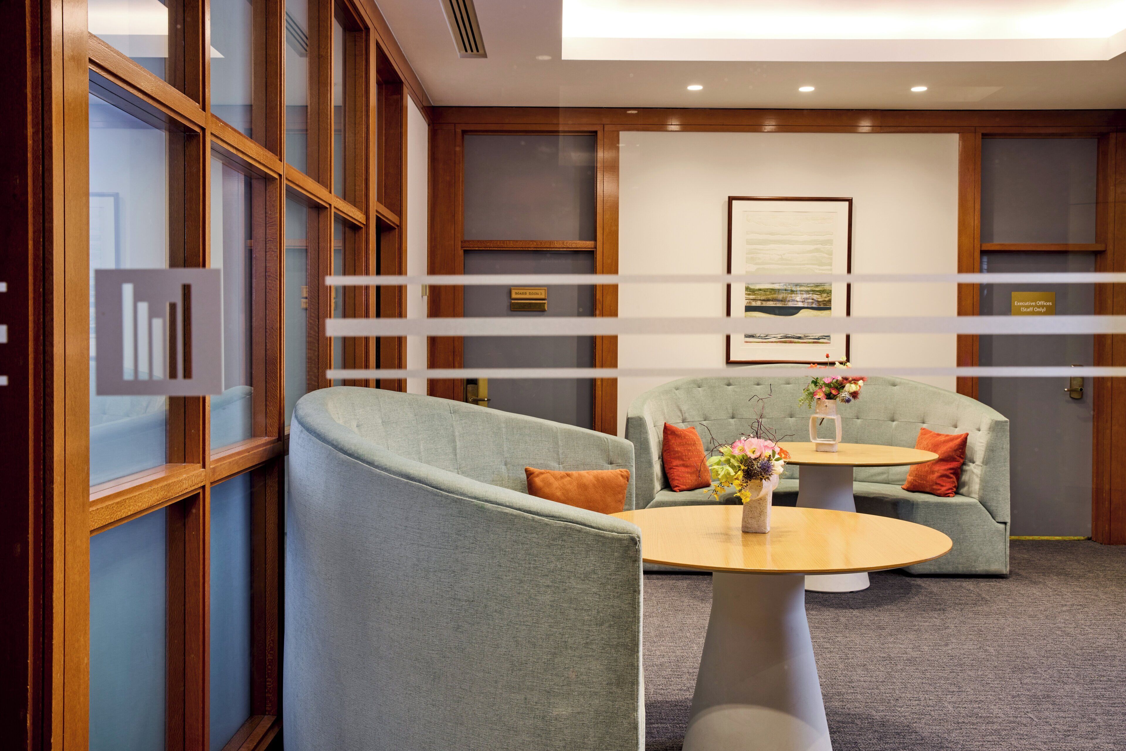 Un espace détente moderne avec deux canapés et une table ronde, agrémenté d’un petit vase de fleurs.