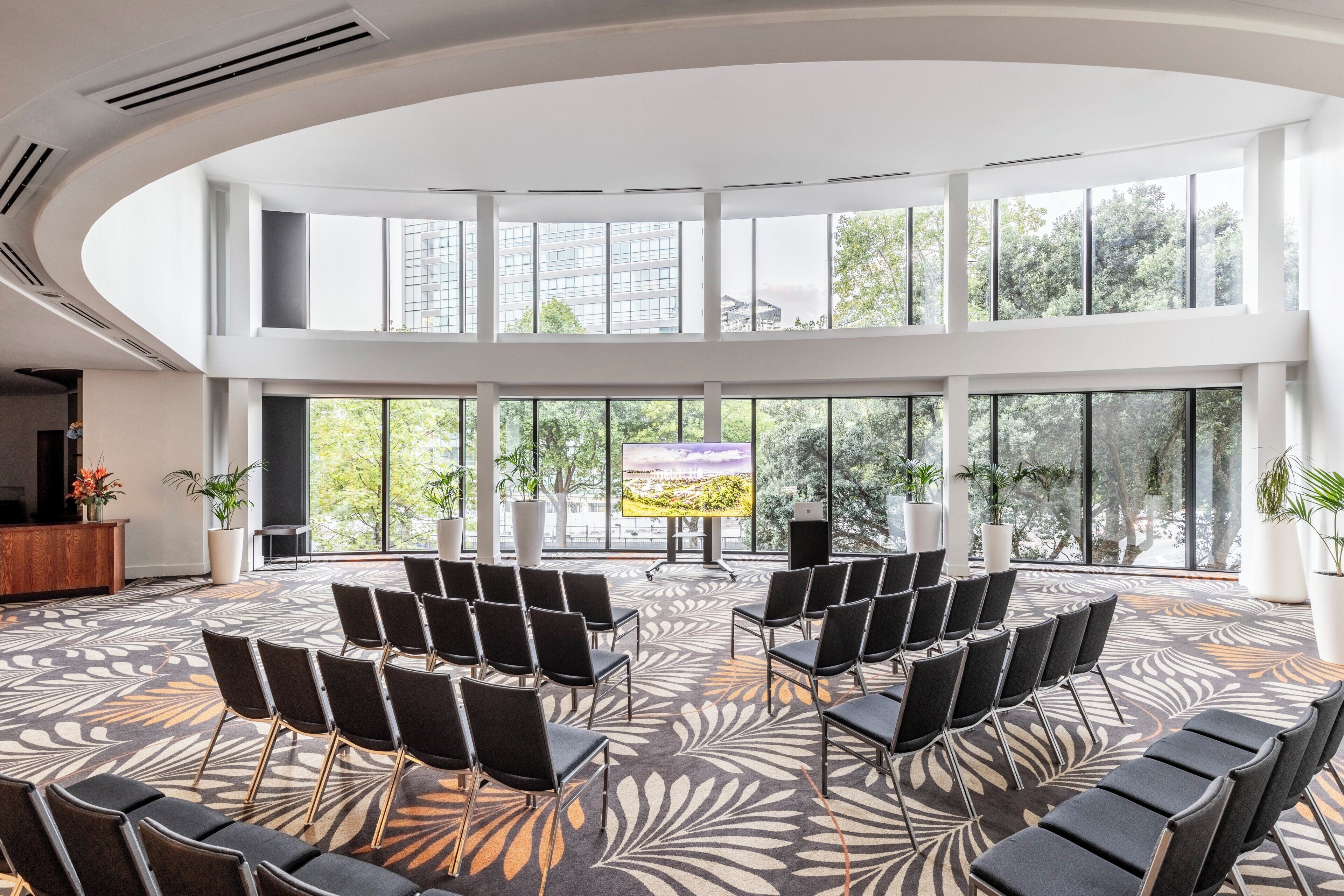 A spacious conference room with tiered seating and large windows offering a view of the outdoors.
