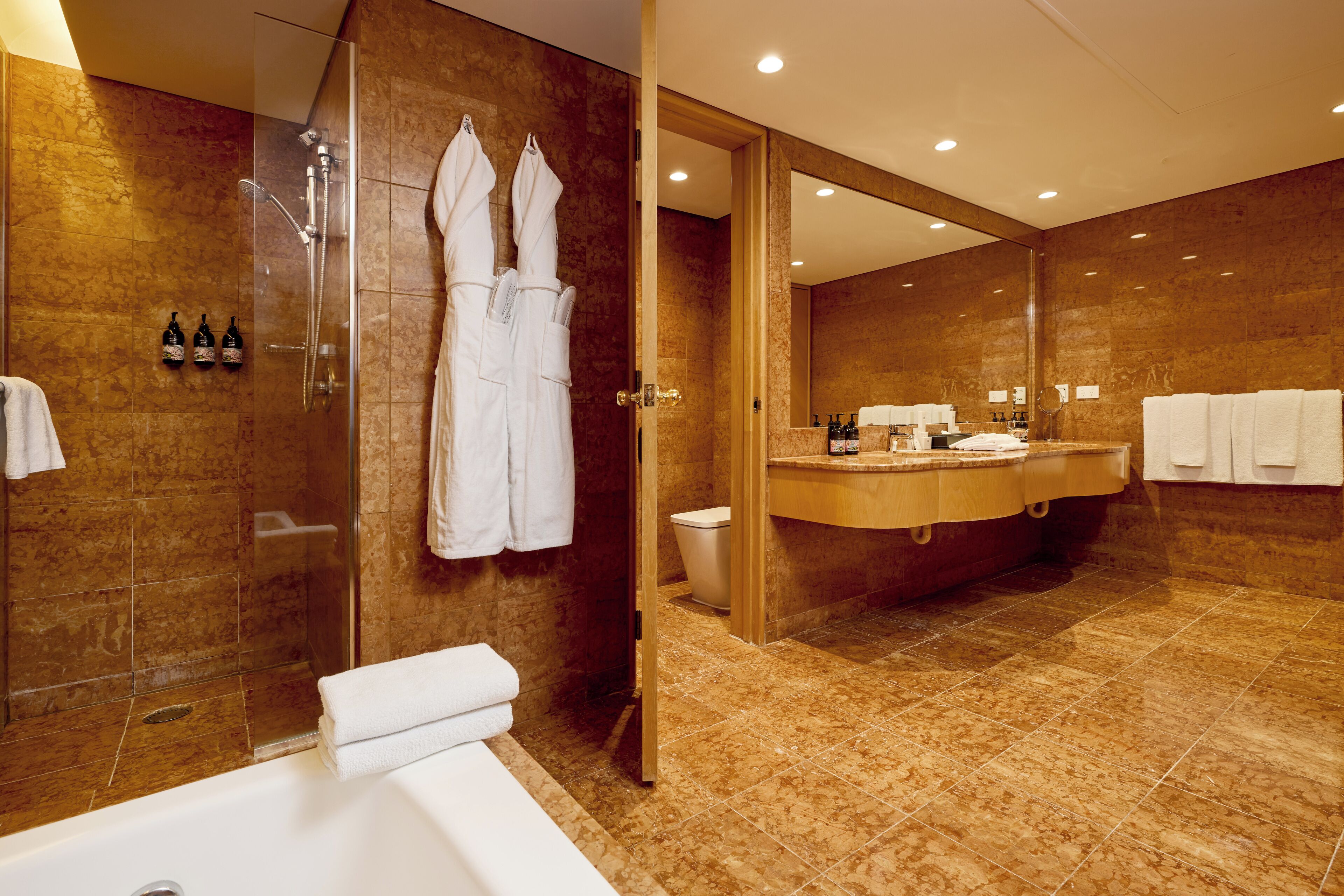 Un baño moderno con ducha envuelta en vidrio, una bañera amplia y un tocador con espejo.