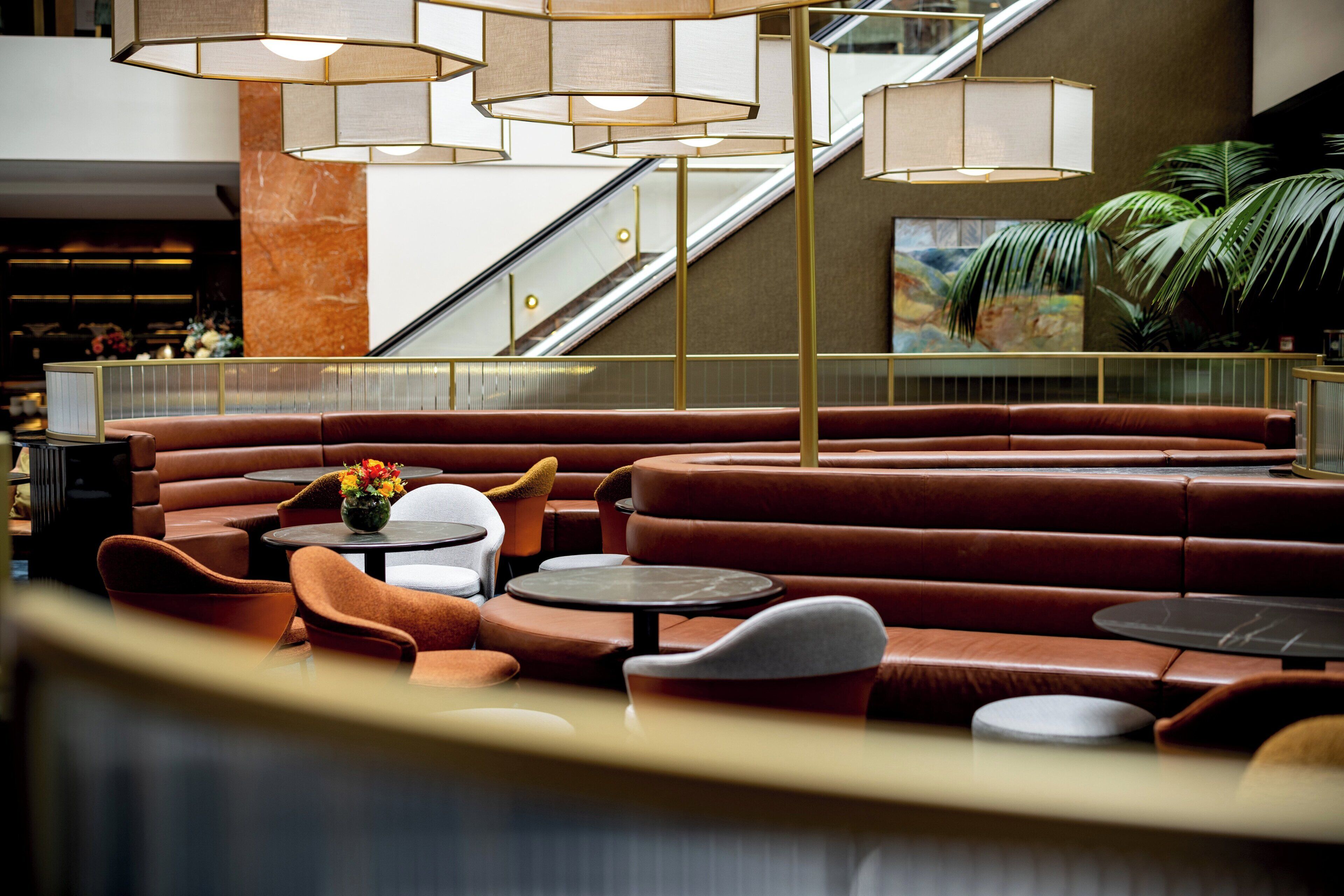 A modern lounge area with leather seating, round tables, and pendant lighting.