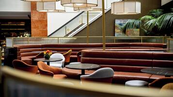 A modern lounge area with leather seating, round tables, and pendant lighting.