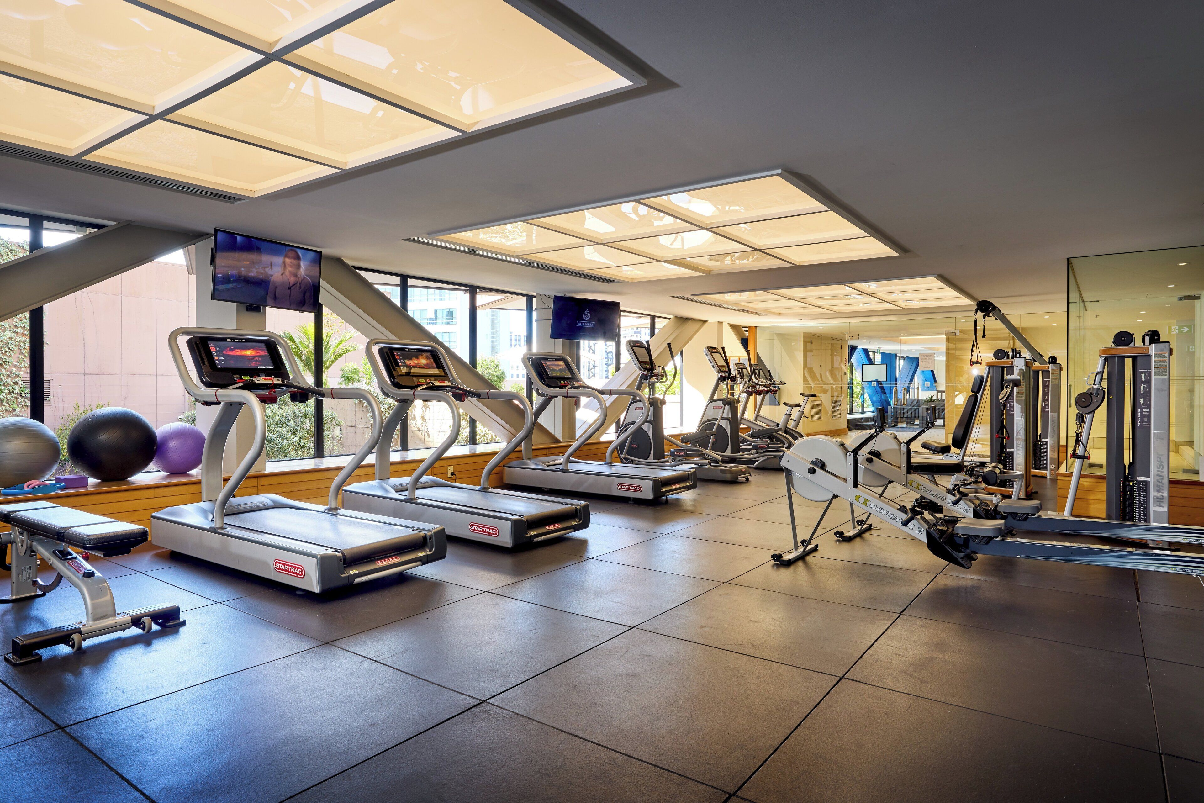 A gym with treadmills, elliptical machines, and exercise balls.
