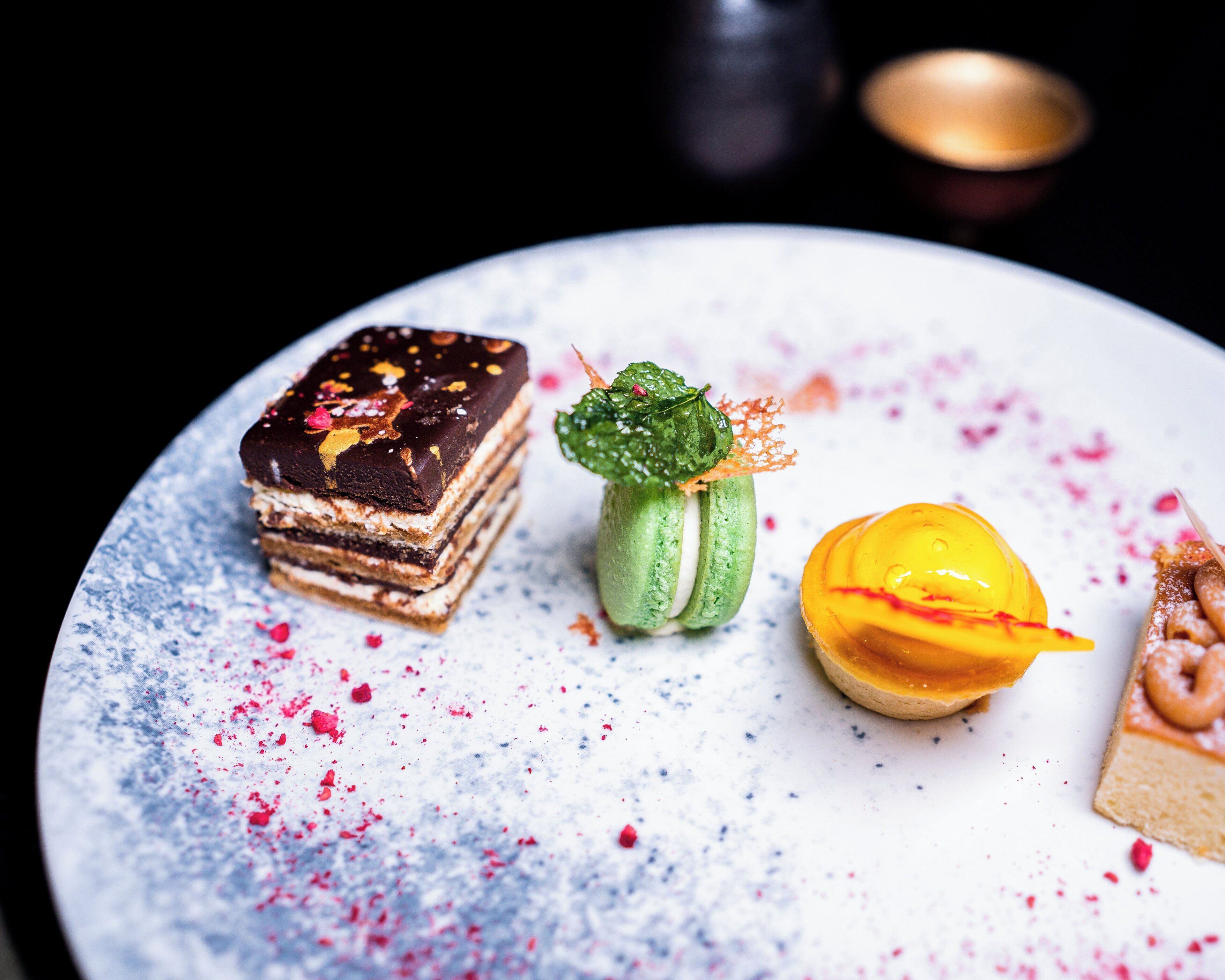 A dessert plate with various pastries and a small green plant.