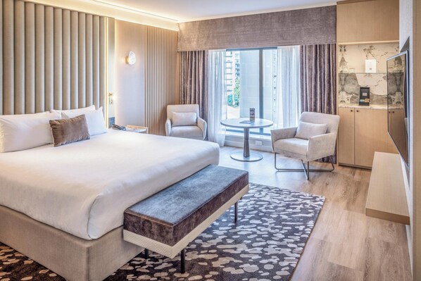 Relax in a spacious room with a large bed, a seating area, and a window offering a view of the outside.