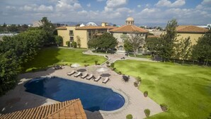 Una piscina con sillas de descanso y un jardín ajardinado.