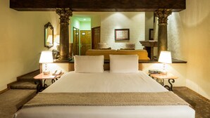 A hotel room with a large bed, two bedside tables with lamps, a mirror, and a view of the hallway.