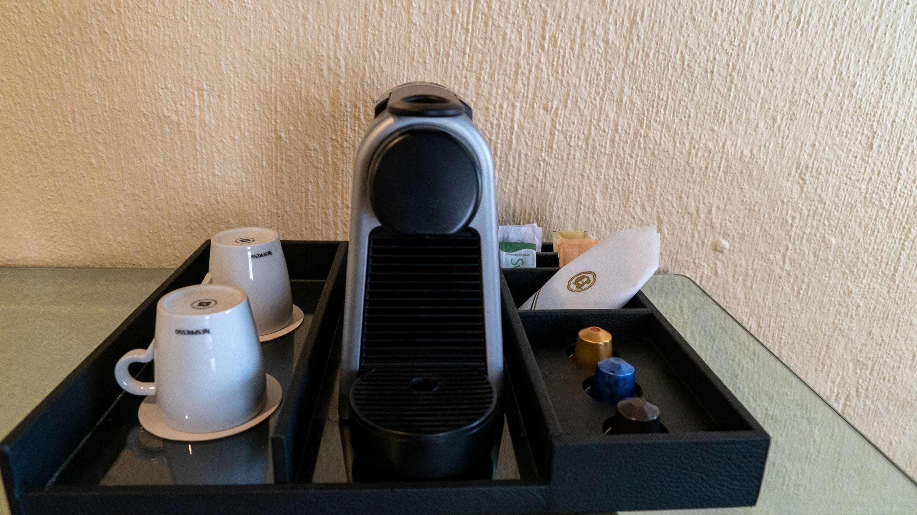 Een koffiezetapparaat, twee kopjes, een dienblad en een klein bakje met deksel.