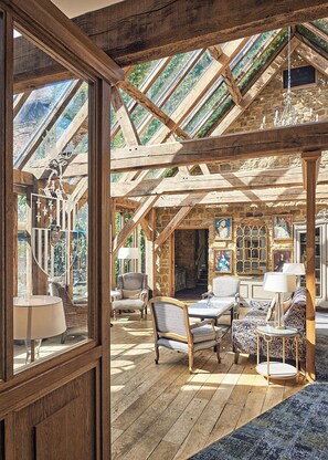 A rustic room with wooden beams, a chandelier, and a view through a window.