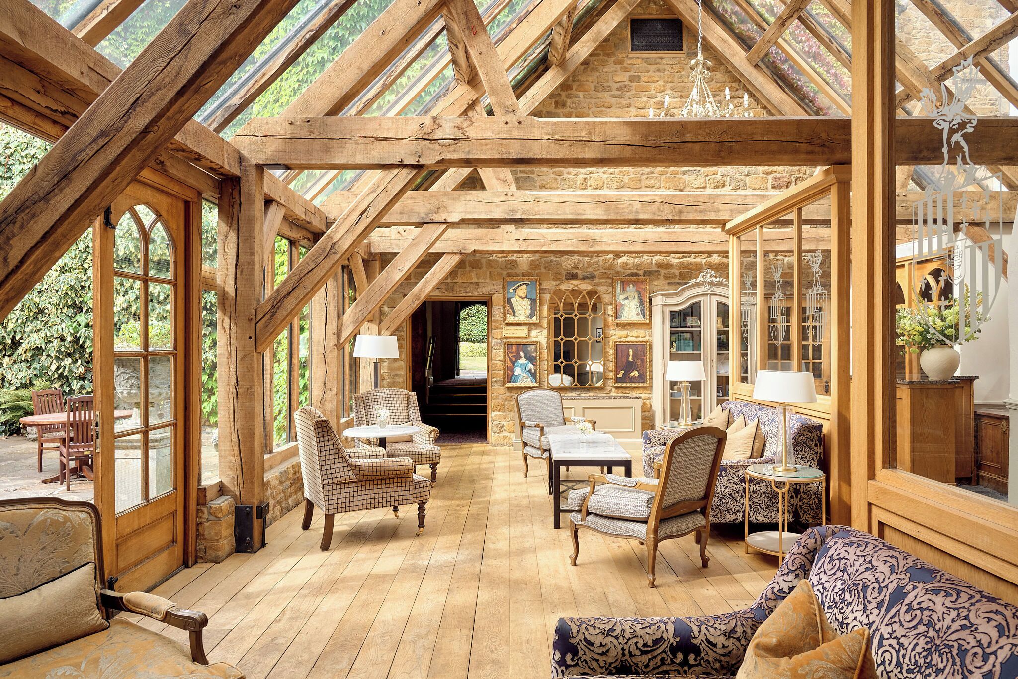 Une pièce spacieuse avec des poutres en bois, de grandes fenêtres et divers types de sièges, notamment des chaises et un canapé.