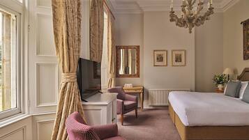 A hotel room with a bed, a television, a chair, a table, and a large window.