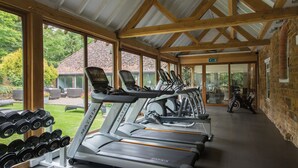 Un gimnasio con cintas de correr, pesas y vistas al exterior.