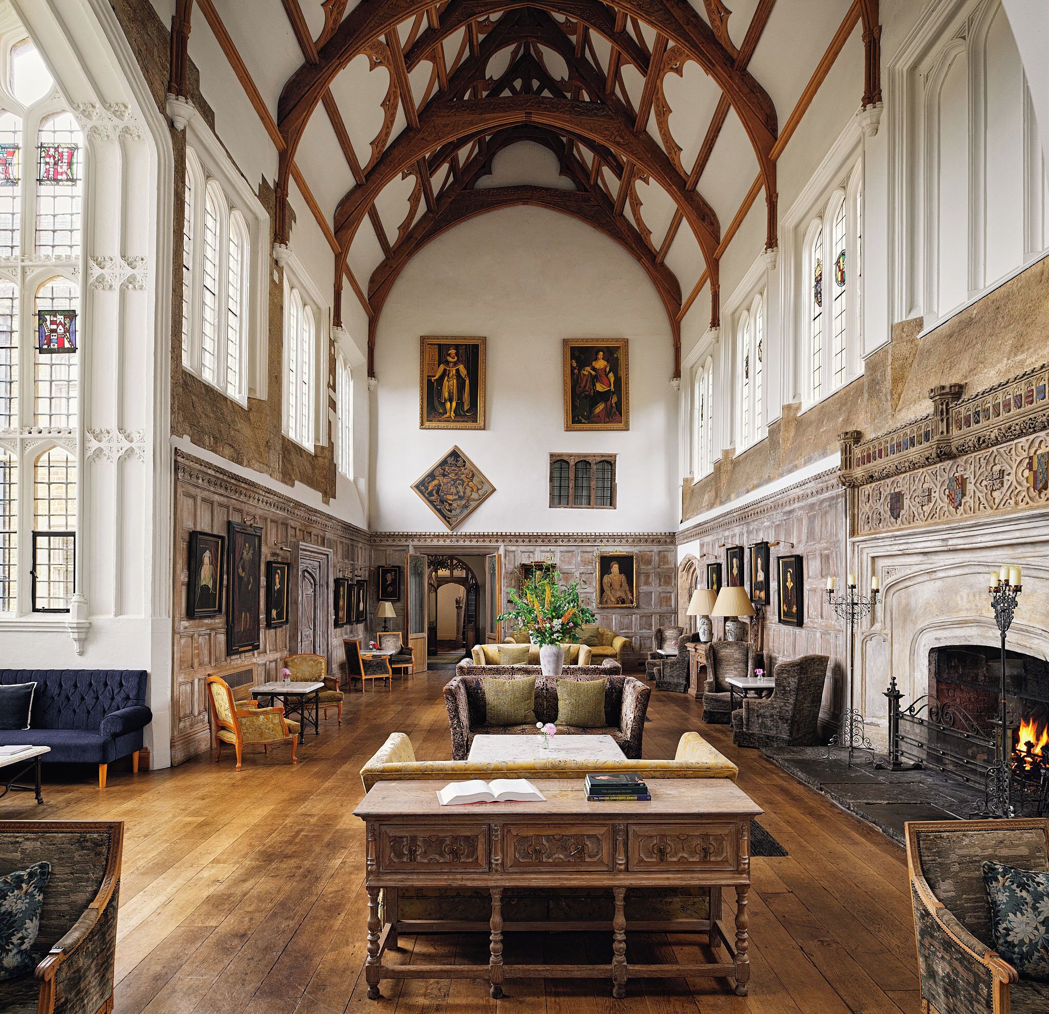 A spacious room with high ceilings, wooden beams, and a fireplace. There are multiple seating areas with tables and chairs.