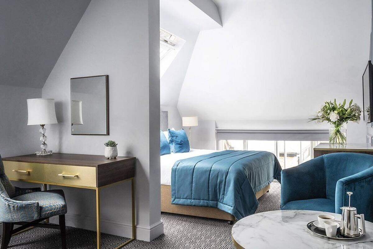 Habitación de hotel moderna con escritorio, silla, cama y zona de estar.