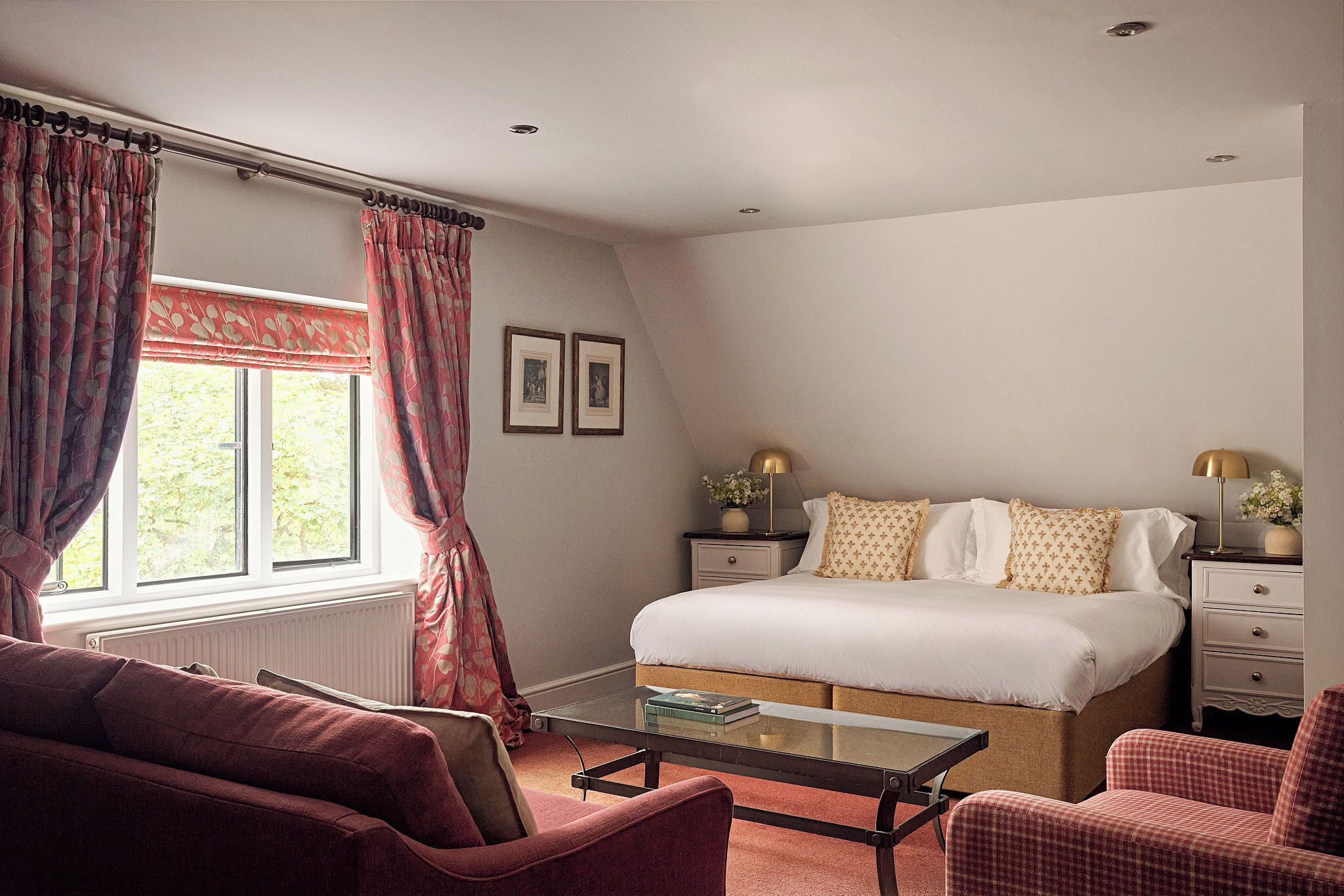 A bedroom with a bed, a bedside table, a chair, a window with curtains, and a radiator.