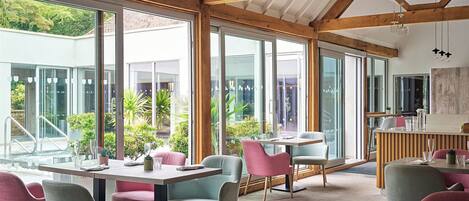 Un comedor moderno con ventanas amplias, vigas de madera y mobiliario contemporáneo.