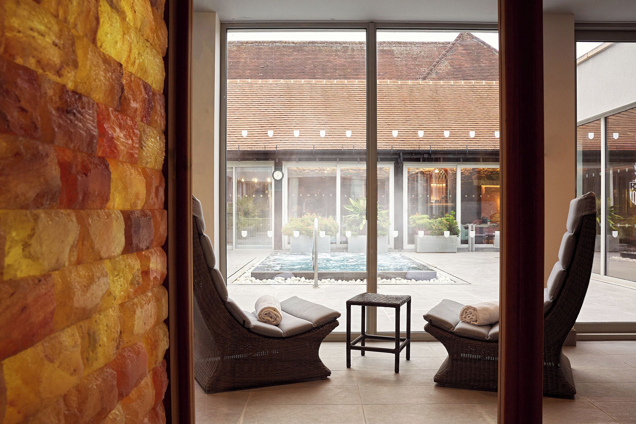 Un interior moderno con un amplio ventanal que da a un espacio exterior con piscina y sillones de descanso.