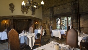 Un restaurante con mesas dispuestas para comer, chimenea y candelabro.