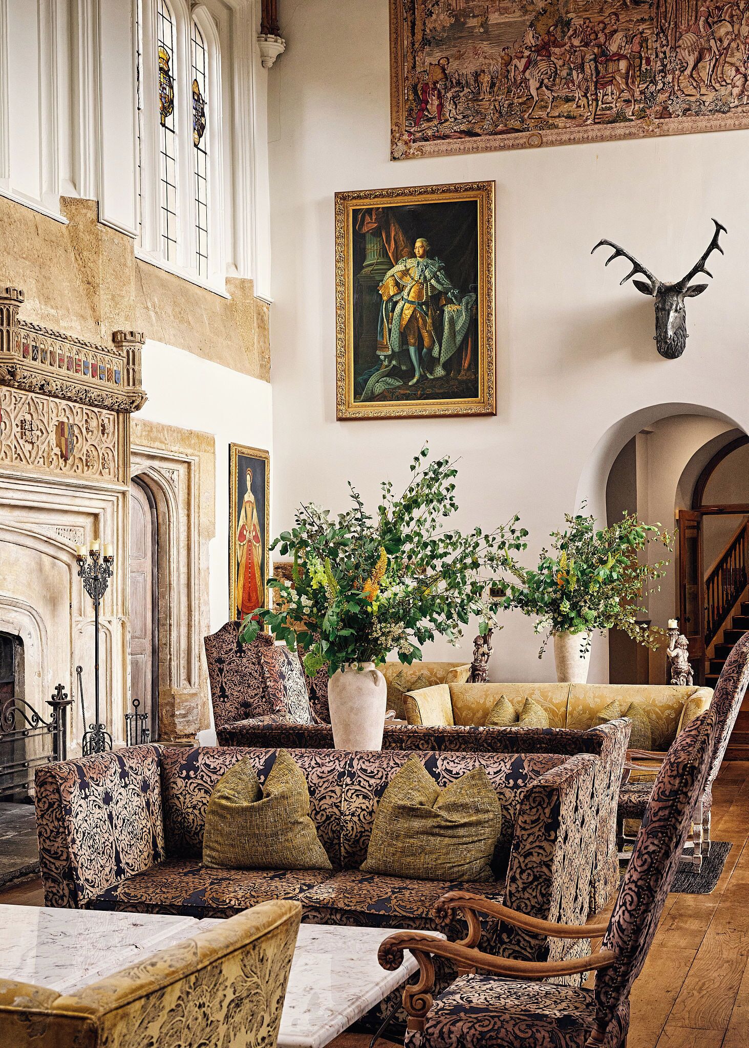 A grand room with a fireplace, ornate furniture, and a large painting.