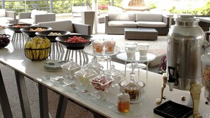 Un buffet proposant une variété de plats et de boissons, notamment des fruits, des desserts et un coin café.