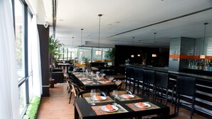Un restaurant moderne avec de longues tables, des chaises noires et un espace bar.