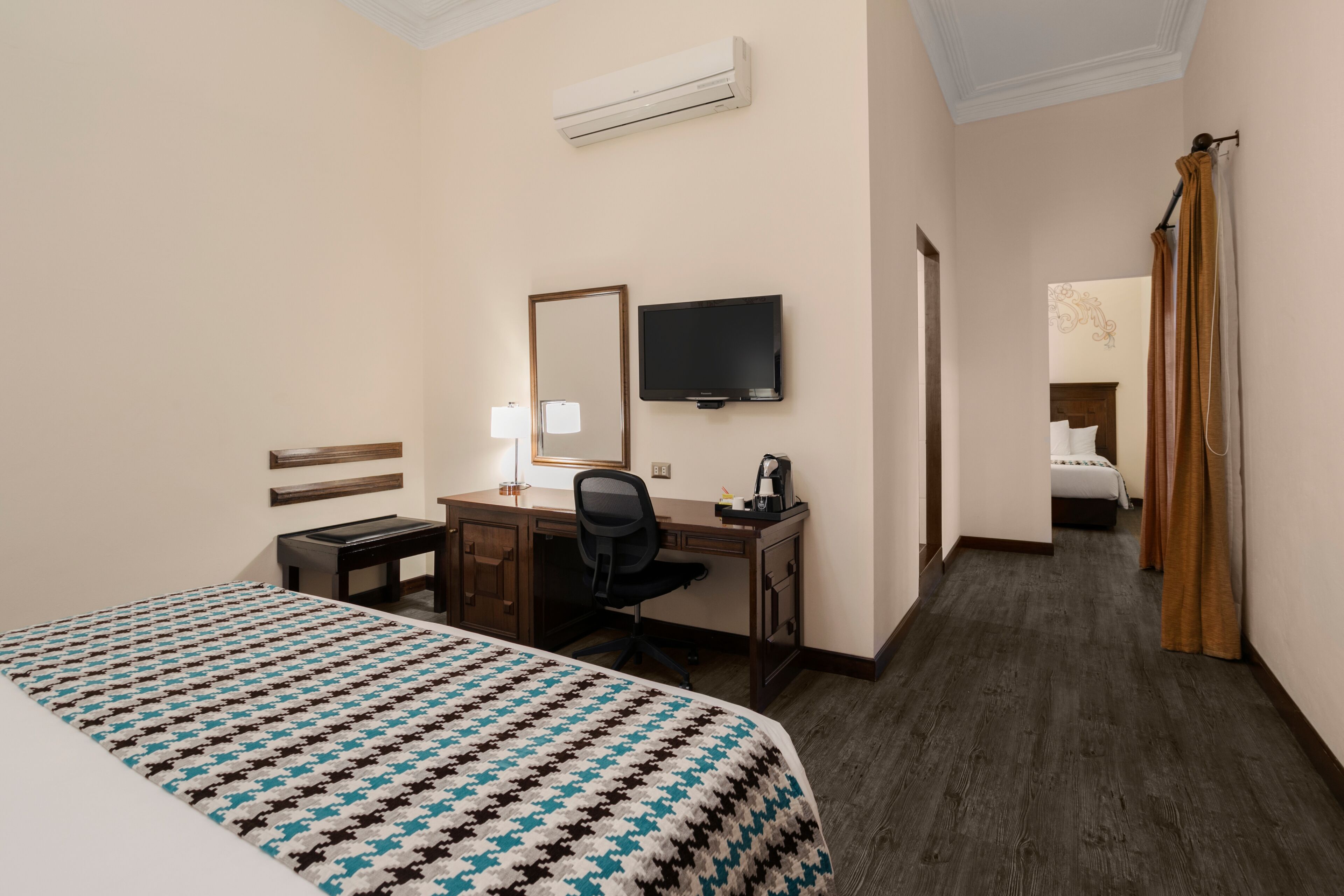 Une chambre d’hôtel équipée d’un lit, d’un bureau, d’une chaise, d’une télévision et d’une salle de bain avec un rideau de douche.