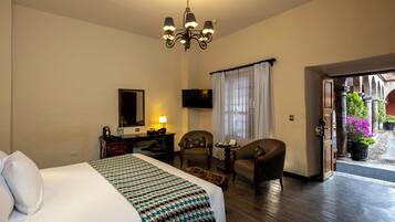 A hotel room with a bed, a desk, a chair, a television, and a view of the outside.