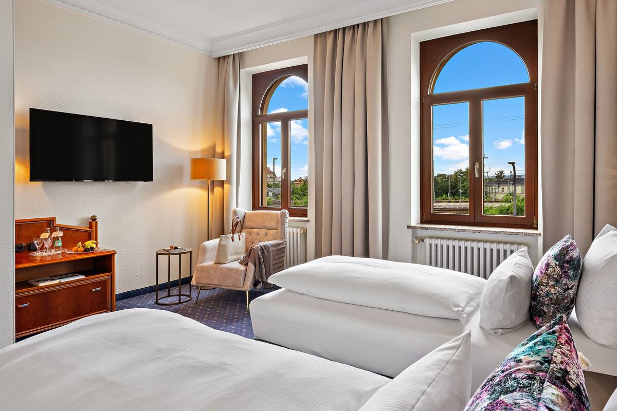 Une chambre d’hôtel avec deux lits, une télévision, un bureau avec une lampe et une vue sur l’extérieur.