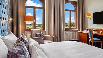 Une chambre d’hôtel avec un lit, deux chaises, un bureau, une lampe et un téléviseur.
