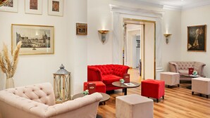 Un elegante rincón de sala con un sofá rojo, sillones color beige y una mesa de centro.