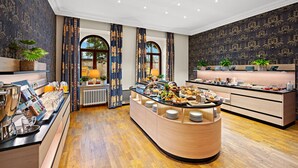 Un bufé de desayuno con gran variedad de alimentos, una estación de café y un área de estar con vistas al exterior.