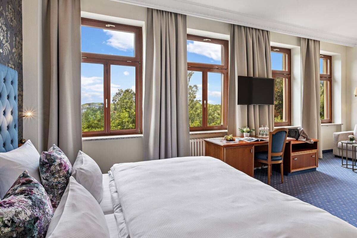 Une chambre d’hôtel avec un grand lit, un bureau avec une chaise, une télévision et un canapé.