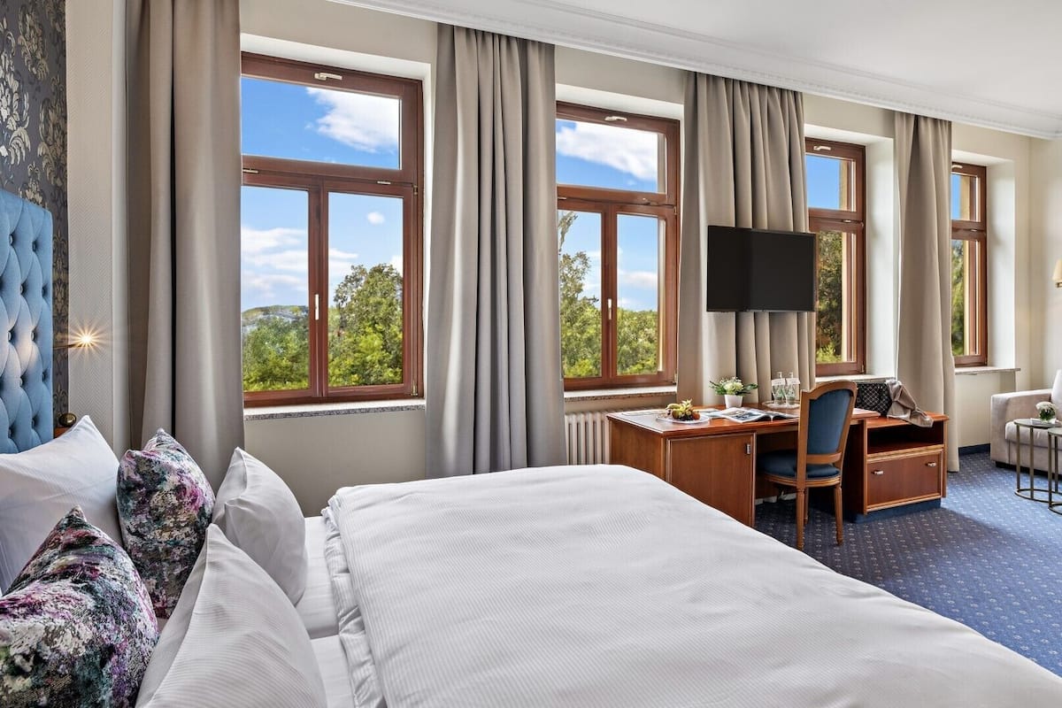 Une chambre d’hôtel avec un grand lit, un bureau avec une chaise, une télévision et un canapé.