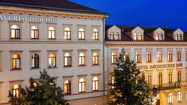 Fachada de hotel con ventanas arqueadas y un cartel que dice "HOTEL BAYERISCHER HOF".