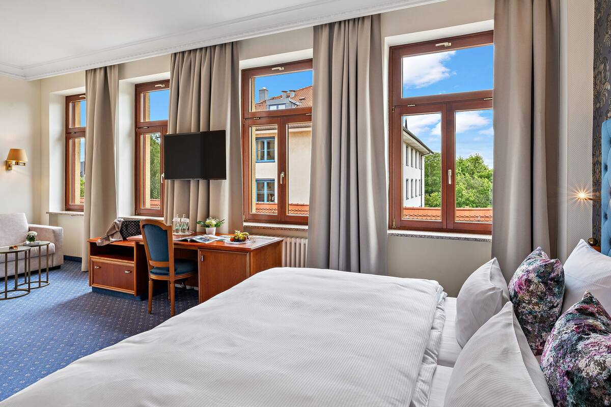 Une chambre d’hôtel avec un grand lit, un bureau avec une chaise, un canapé et un téléviseur.