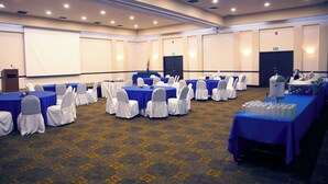 A conference room with multiple tables, chairs, and a projector screen.