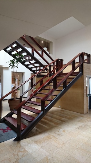 A modern staircase with a wooden handrail and glass panels, leading to an upper level. - Casa Grande Chihuahua (Chihuahua)
