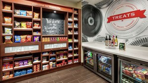 A snack display with various chips and snacks, a chalkboard sign, and a 'Treats' sign on the wall. - Hampton Inn & Suites Dallas-Mesquite (Mesquite)