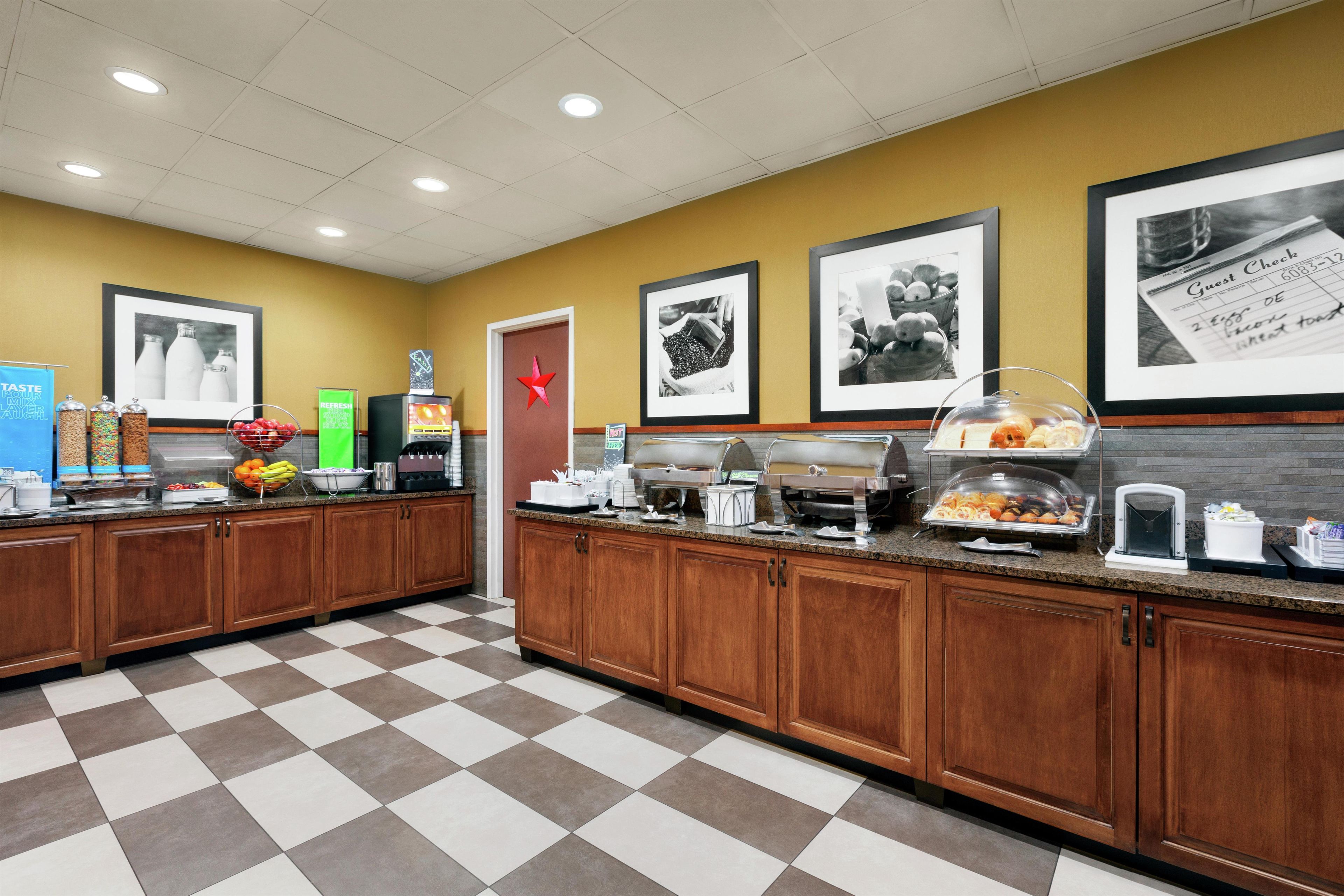 A hotel breakfast area with a check-in counter, a coffee station, and a fruit display.