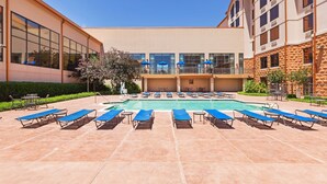 A pool area with sun loungers and a building with large windows and a stone facade. - Hampton Inn & Suites Dallas-Mesquite (Mesquite)
