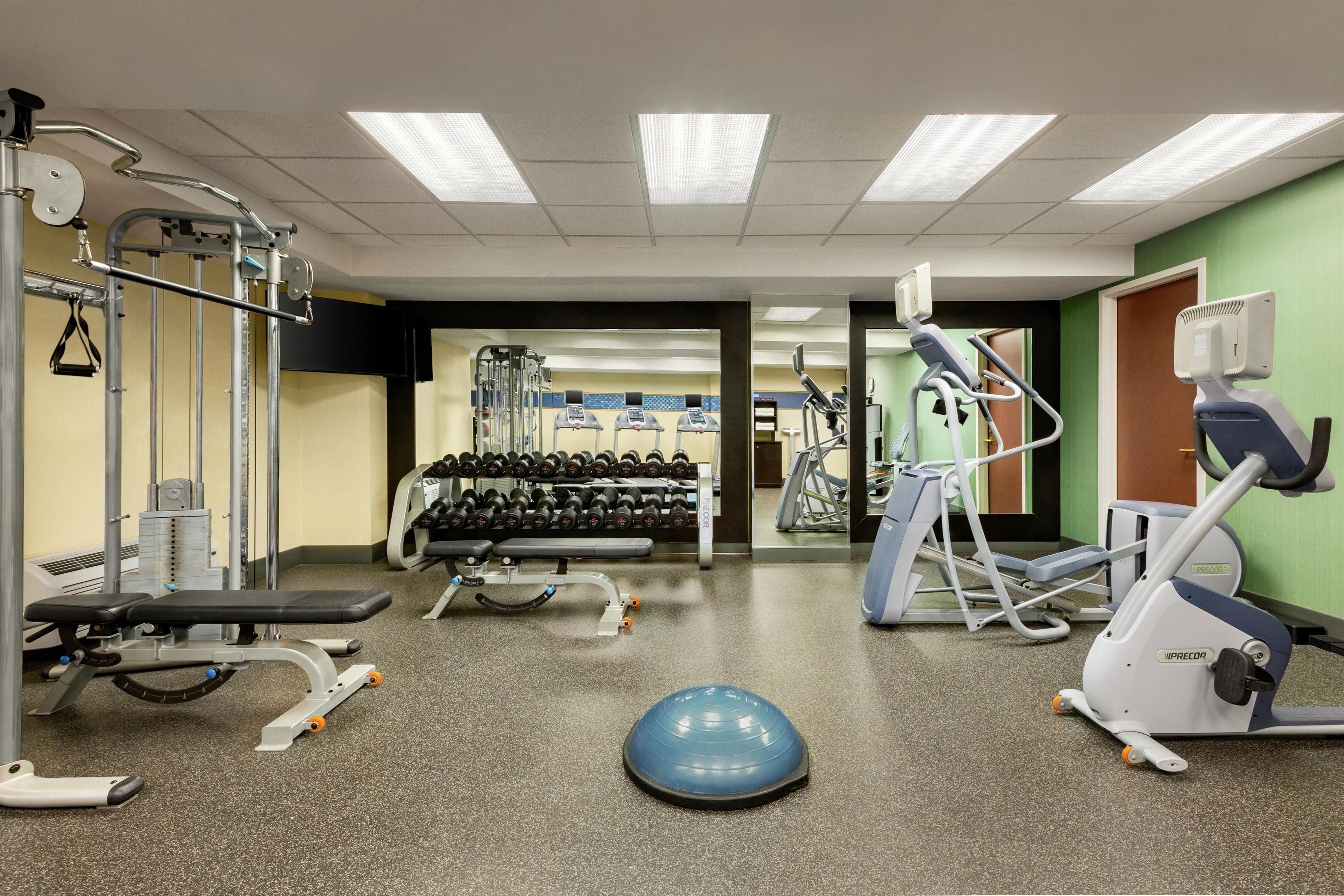 A gym with various exercise equipment including treadmills, weight machines, and free weights.