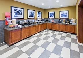 A hotel kitchen with buffet setup, including a grill, hot food station, and various food containers.
