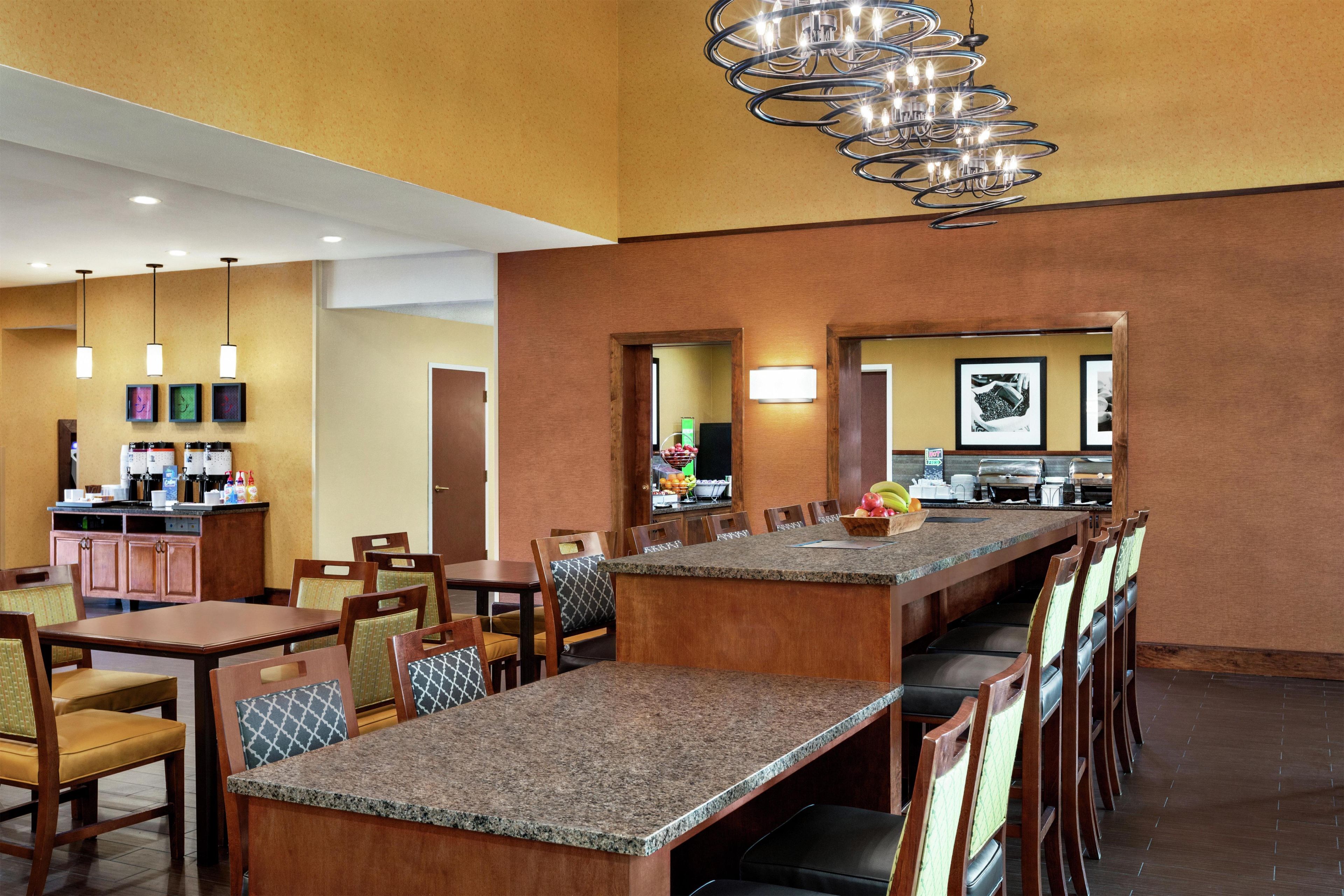 A hotel lobby with a long bar, seating area, and a coffee station.