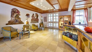 A spacious lobby with wooden ceiling beams, a large window with curtains, and a reception desk with a pumpkin decoration. - Hotel LinderHof Erfurt (Erfurt)