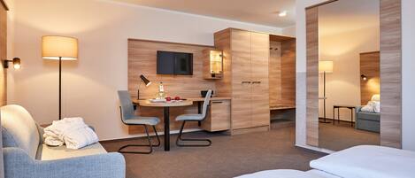 Ein modernes Hotelzimmer mit einem Bett, einem Schreibtisch mit Stuhl, einem Flachbildfernseher und einem Kleiderschrank.