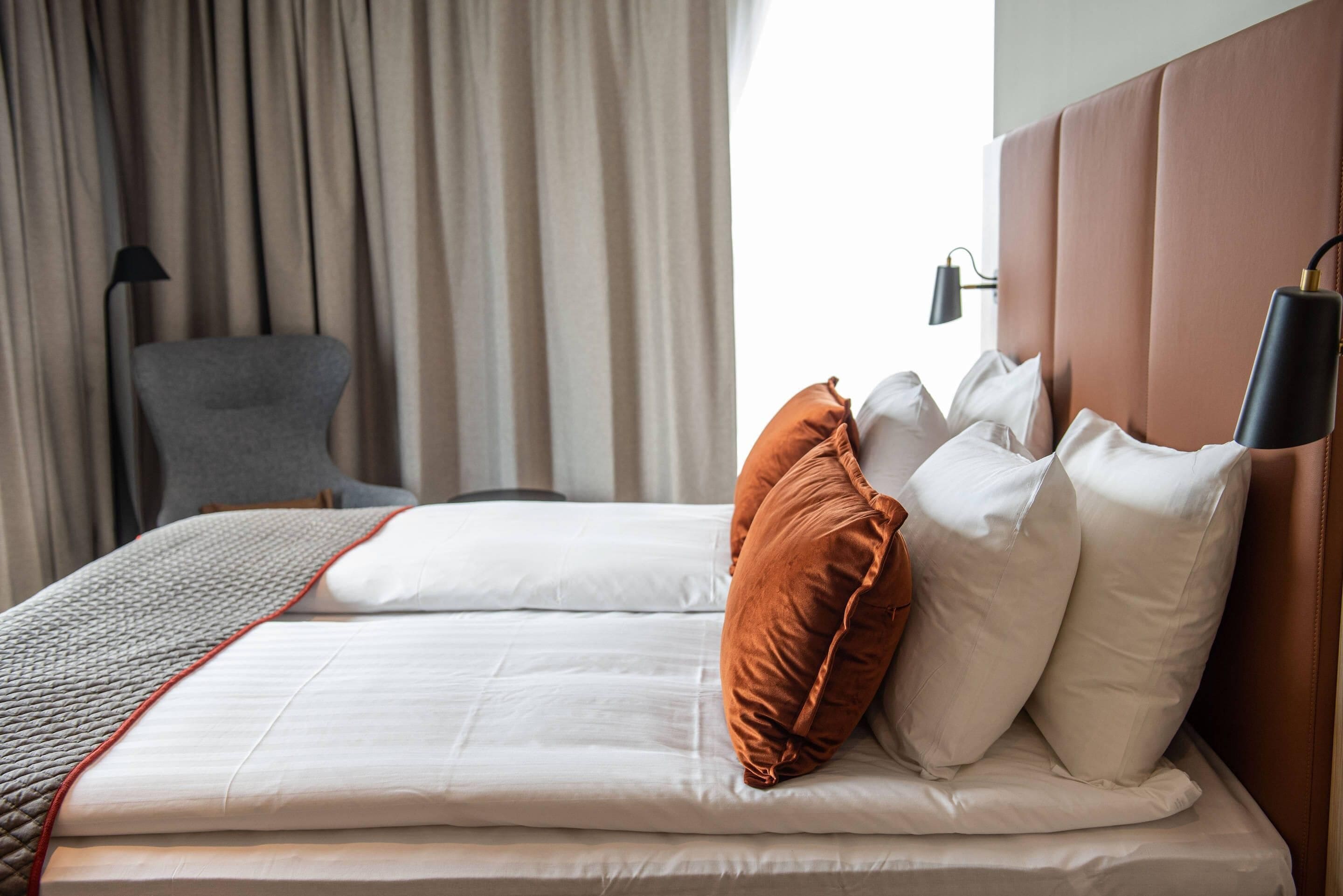 Ein Hotelzimmer mit einem ordentlich bezogenen Bett, einem Sessel und einer Lampe.